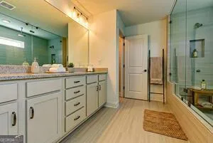 a spacious bathroom with a double vanity sink a large mirror and shower