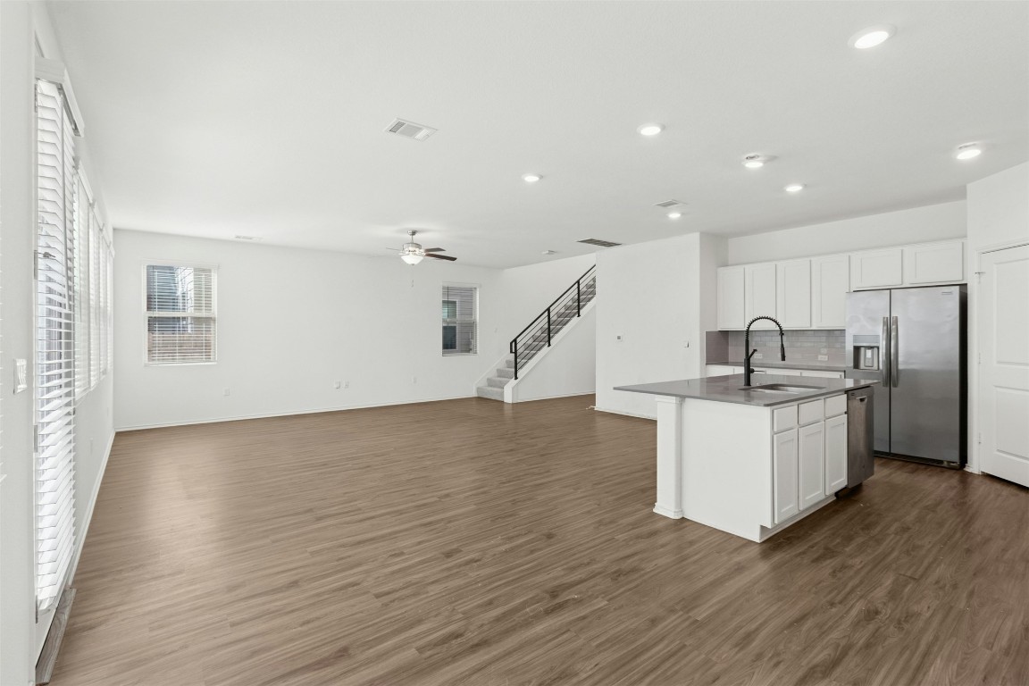 10405 Tree Duck Drive Austin, TX 78748 - Photo 33 of 33 Kitchen featuring open floor plan, white cabinetry, appliances with stainless steel finishes, a center island with sink, and dark wood-type flooring