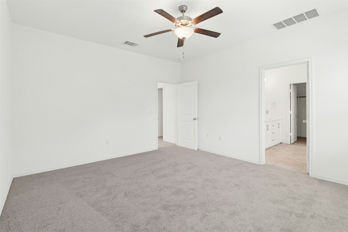 10405 Tree Duck Drive Austin, TX 78748 - Photo 17 of 33 Unfurnished bedroom featuring light colored carpet, a ceiling fan, and ensuite bathroom