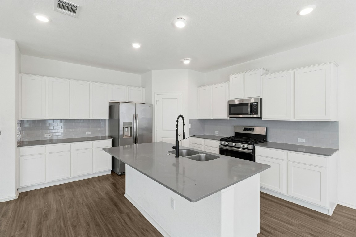 10405 Tree Duck Drive Austin, TX 78748 - Photo 8 of 33 Kitchen with appliances with stainless steel finishes, decorative backsplash, white cabinetry, dark wood-style floors, and recessed lighting