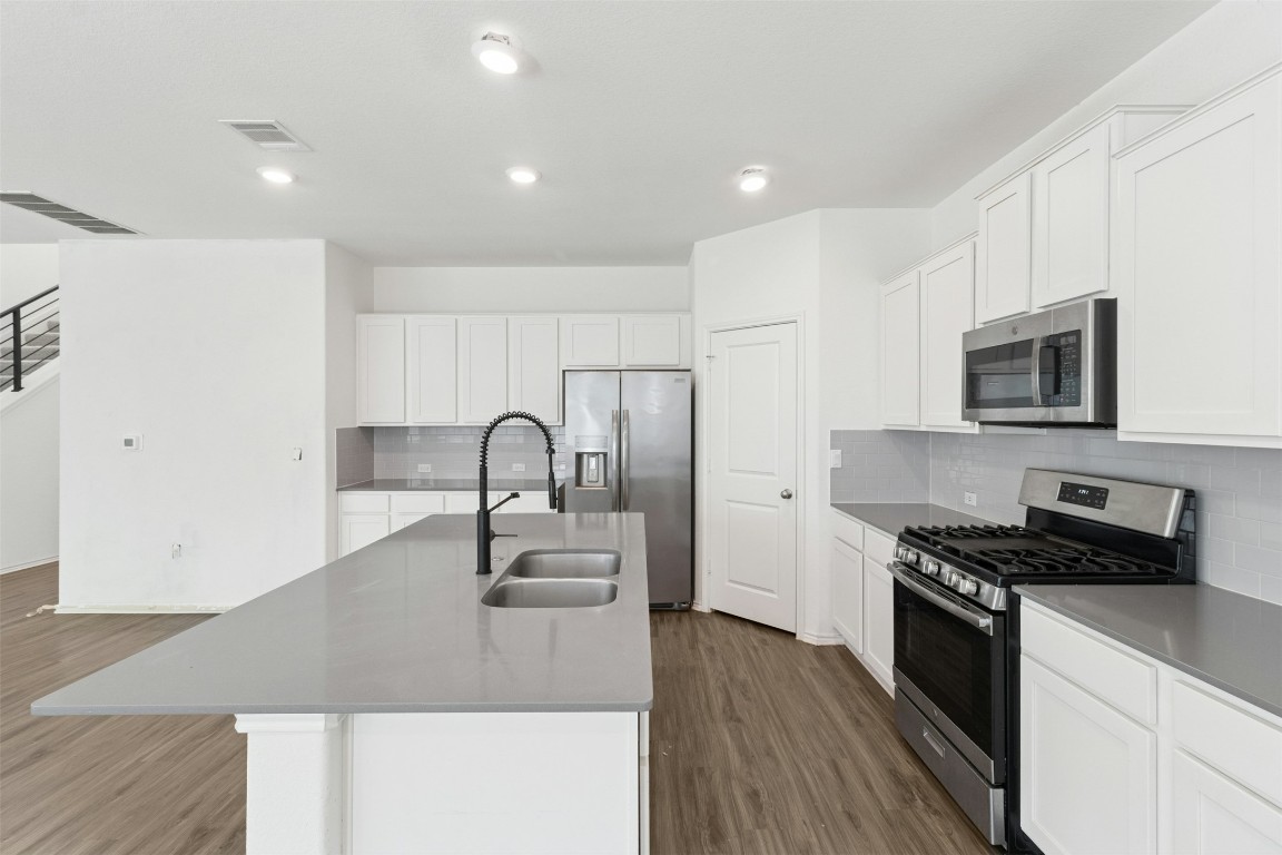10405 Tree Duck Drive Austin, TX 78748 - Photo 10 of 33 Kitchen featuring stainless steel appliances, dark wood finished floors, backsplash, white cabinetry, and recessed lighting