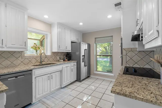 a bathroom with a granite countertop sink a toilet a window and a mirror