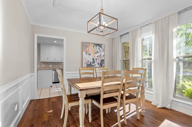 a dining room with wooden floor a chandelier a wooden table and chairs