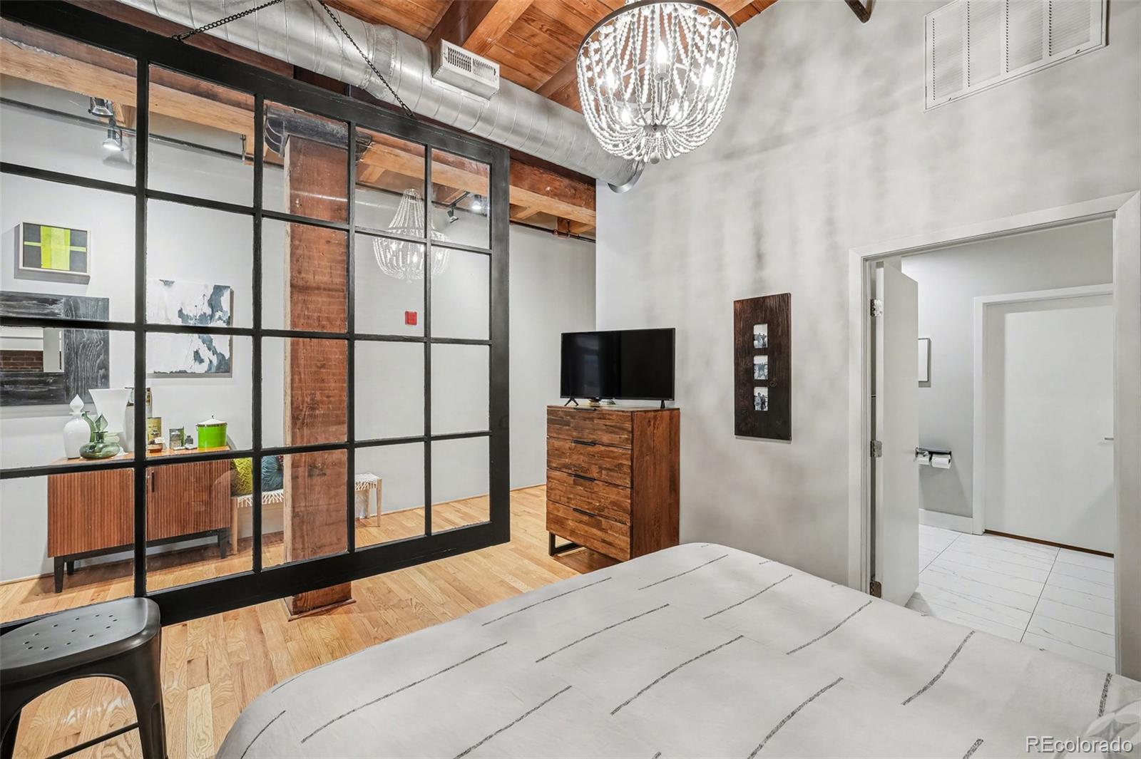 2960 Inca Street, Unit 103 Denver, CO 80202 - Photo 9 of 28 a bedroom with a bed and a flat tv screen on the dresser