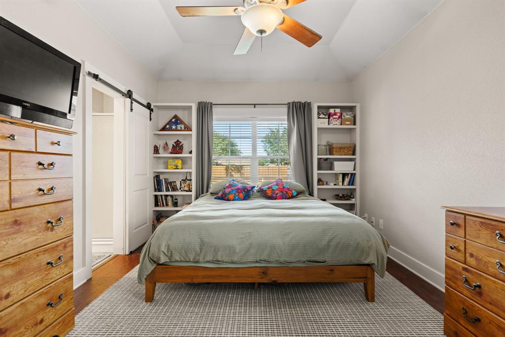 10609 Aquilla Trail Waco, TX 76708 - Photo 22 of 30 Vaulted ceiling featuring a ceiling fan, recessed window with blinds, built-in shelving, wood-finish flooring, and a barn door