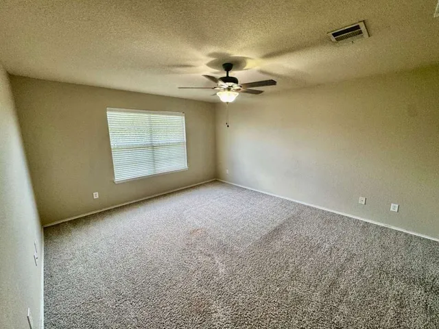 an empty room with windows and ceiling fan
