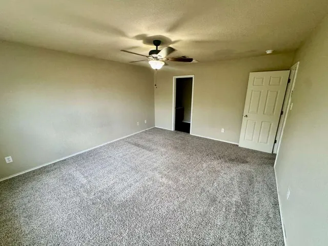 a view of an empty room with a chandelier fan