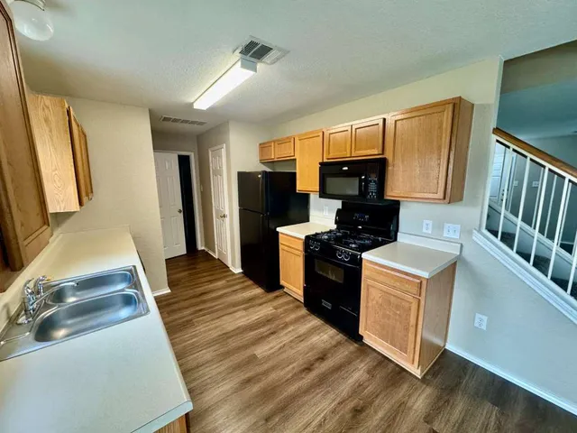 a kitchen with granite countertop a refrigerator stove top oven and sink