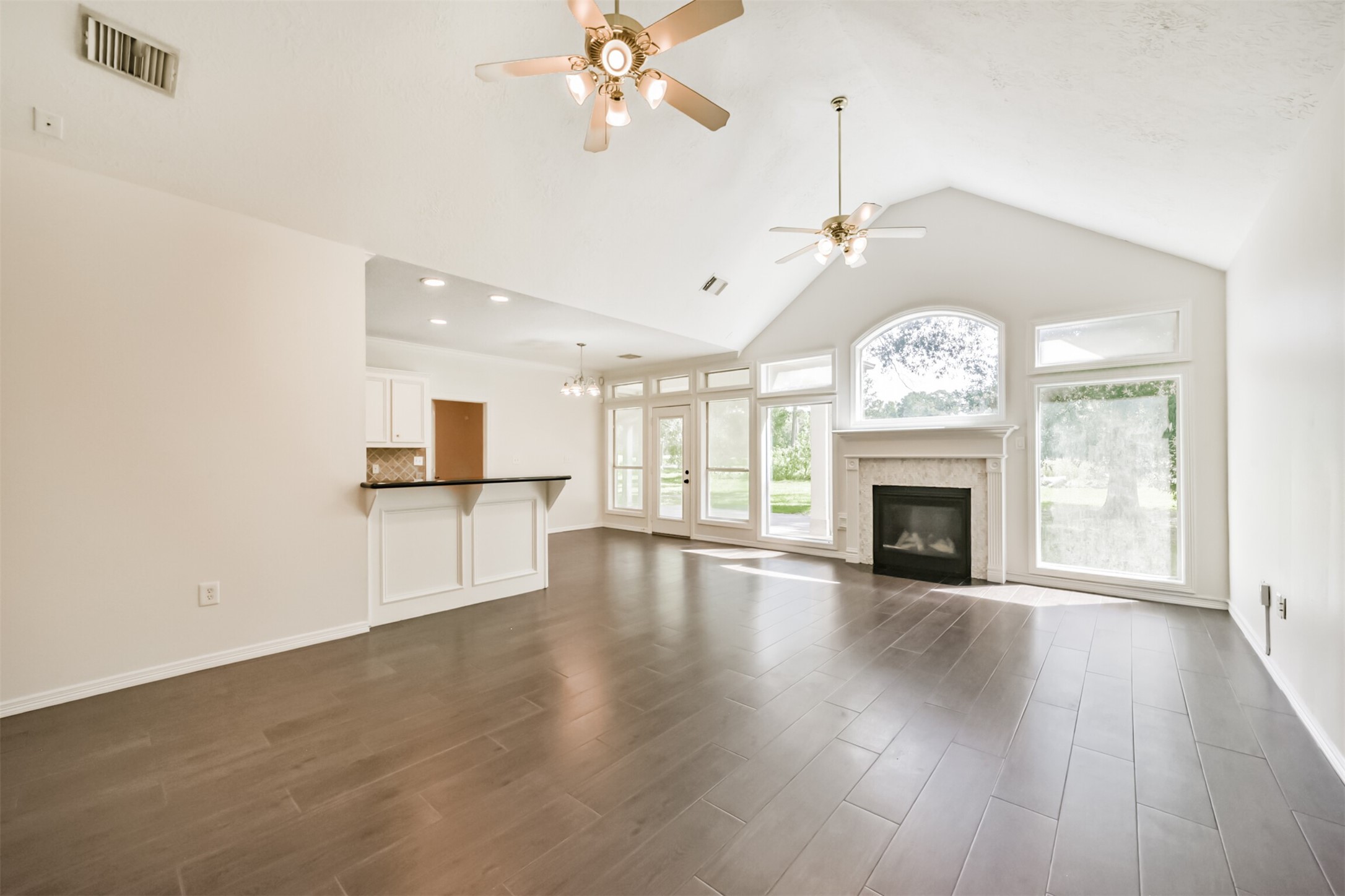 27322 Afton Way Huffman, TX 77336 - Photo 12 of 50 Spacious living area features vaulted ceilings, wood-look tile flooring, oversized windows, and a cozy fireplace as the focal point.