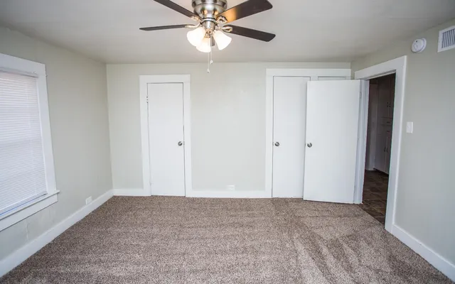 a view of an empty room and chandelier fan