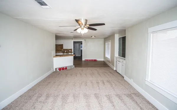 a living room with stainless steel appliances kitchen island granite countertop wooden floor and cabinets