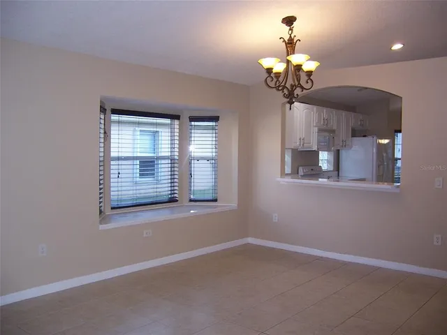 a dining room with wooden floor a chandelier a potted plant and windows