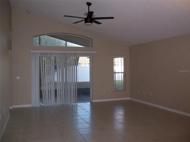 an empty room with wooden floor chandelier fan and windows