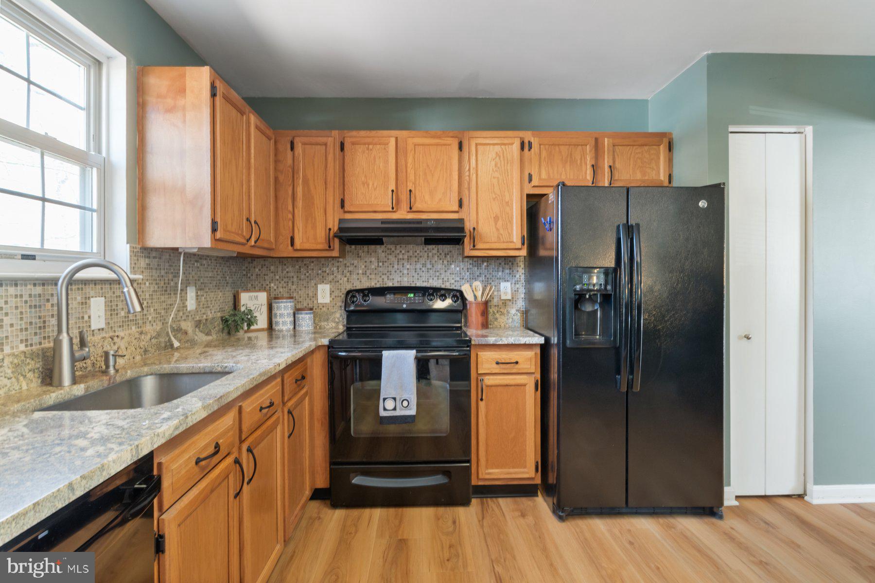 1512 Pullman Drive Severn, MD 21144 - Photo 8 of 34 a kitchen with stainless steel appliances granite countertop a refrigerator a sink dishwasher a stove and white countertops with wooden floor