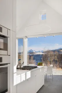 a large white kitchen with a sink and a large window