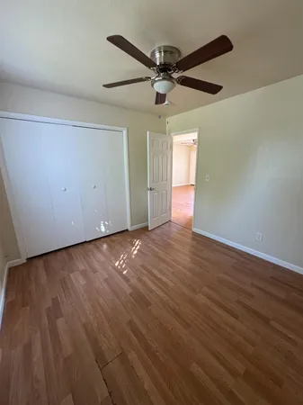 an empty room with wooden floor a ceiling fan and windows