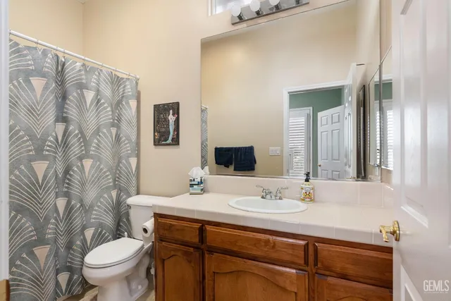 a bathroom with a granite countertop sink a toilet and a mirror