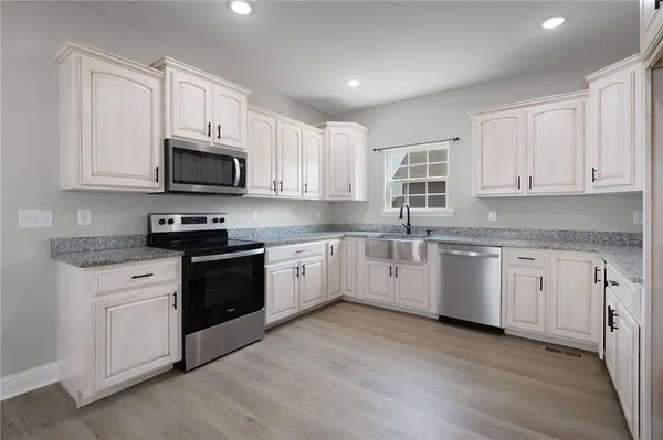 a kitchen with granite countertop white cabinets and white appliances