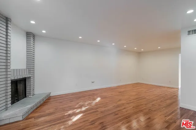 a view of empty room with wooden floor and fireplace