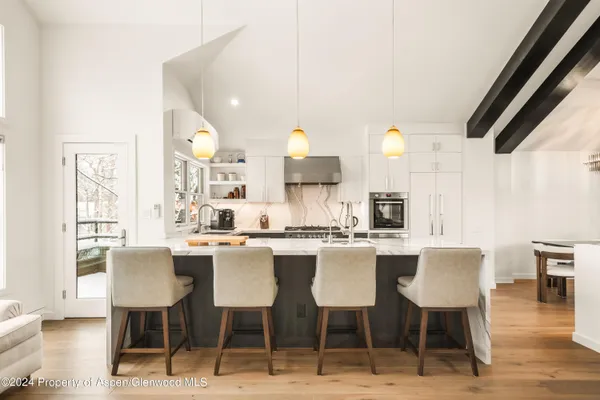 a kitchen with a dining table chairs and wooden floor