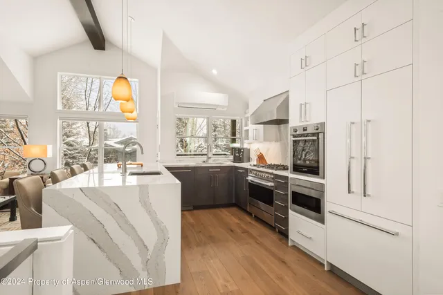 a kitchen with stainless steel appliances white cabinets and wooden floor