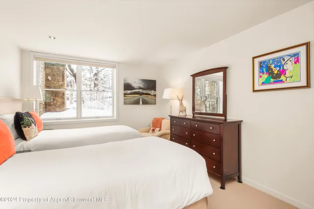 a bedroom with a bed and a lamp on dresser next to a window