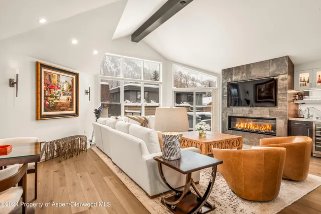 a living room with furniture a flat screen tv and kitchen view