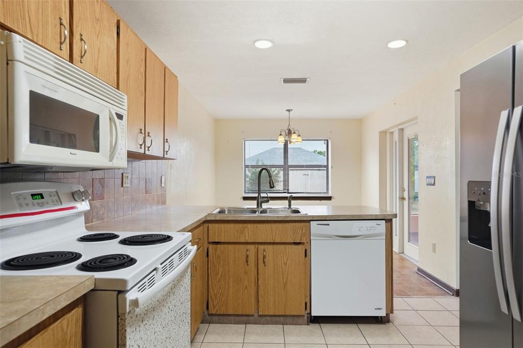 11286 Roland Street Spring Hill, FL 34609 - Photo 13 of 54 a kitchen with stainless steel appliances granite countertop a sink stove and refrigerator