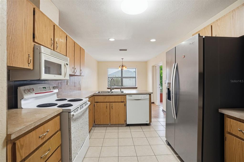 11286 Roland Street Spring Hill, FL 34609 - Photo 14 of 54 a kitchen with stainless steel appliances granite countertop a refrigerator sink and stove