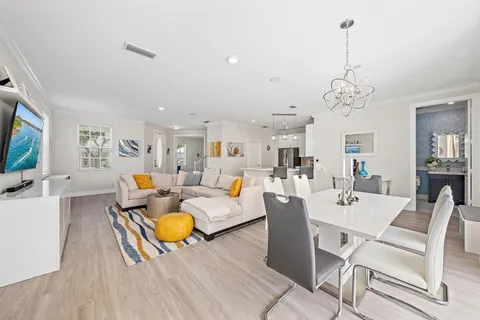 a living room with lots of white furniture and a chandelier