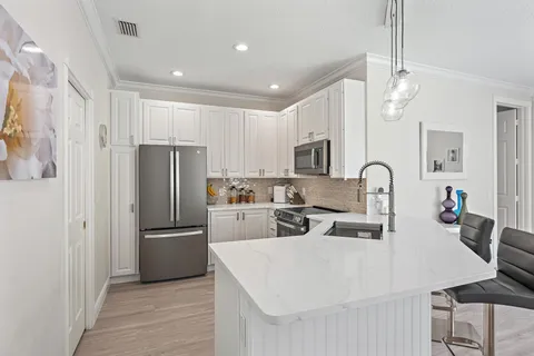 a kitchen with stainless steel appliances a refrigerator a sink a stove a table and chairs
