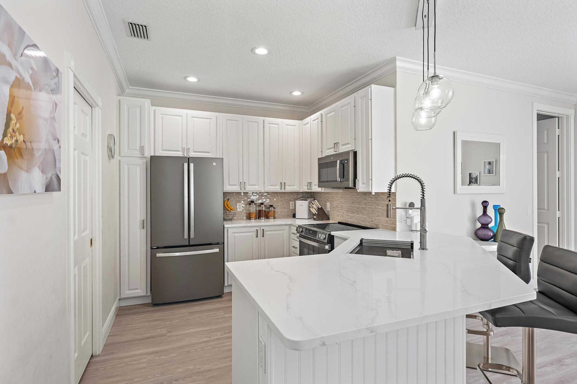 166 Honeysuckle Drive Jupiter, FL 33458 - Photo 4 of 26 a kitchen with stainless steel appliances a refrigerator a sink a stove a table and chairs
