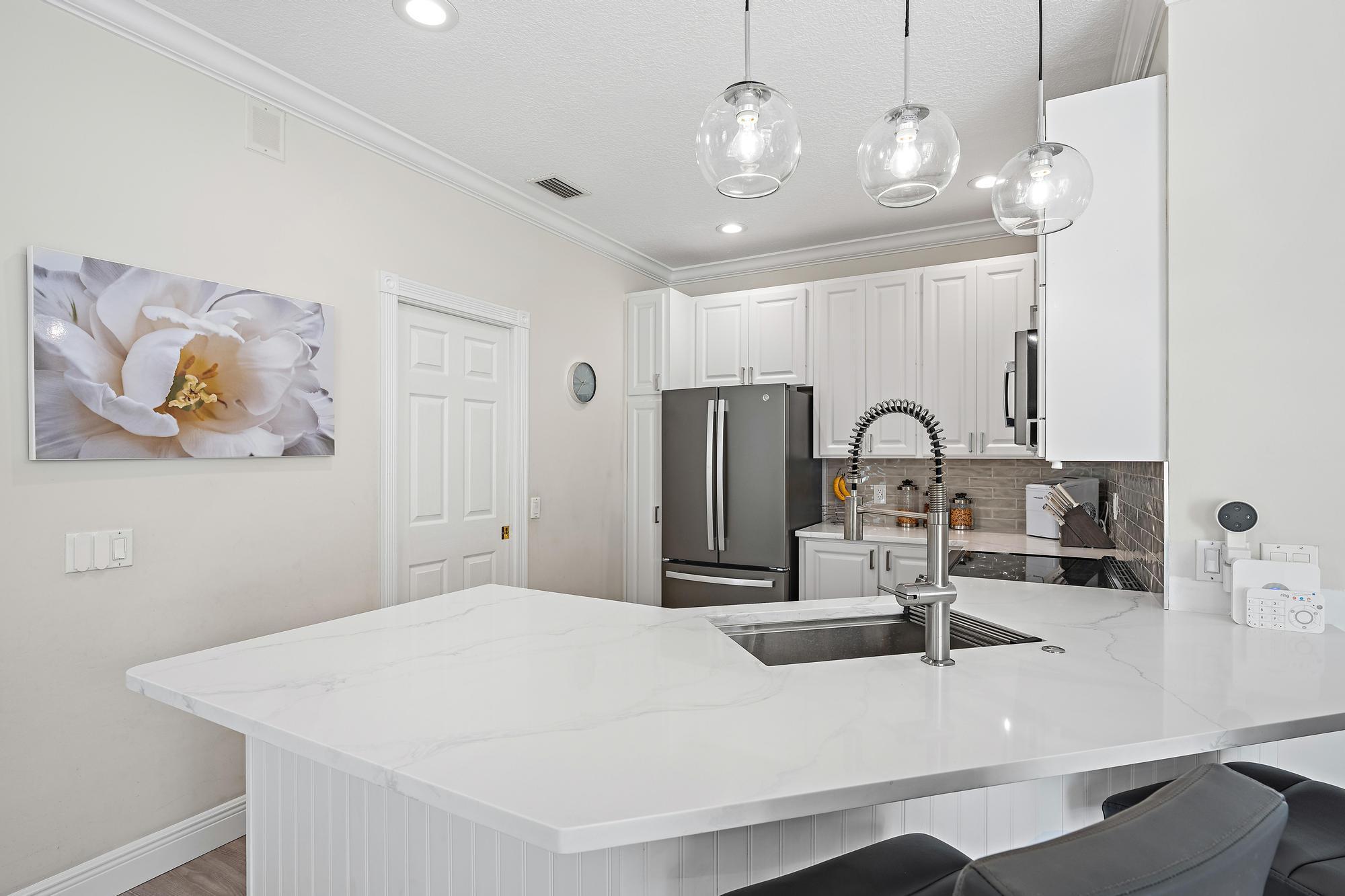 166 Honeysuckle Drive Jupiter, FL 33458 - Photo 6 of 26 a kitchen with kitchen island a sink and a counter top space