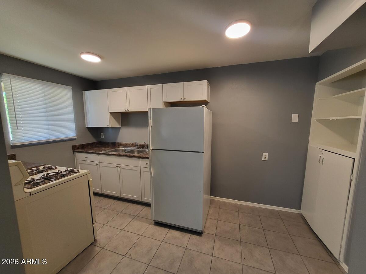 1445 South Kenneth Place, Unit H Tempe, AZ 85281 - Photo 5 of 7 a kitchen with a refrigerator a stove top oven and cabinets