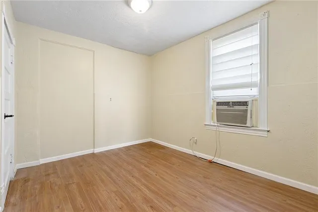 a view of an empty room with wooden floor and a window
