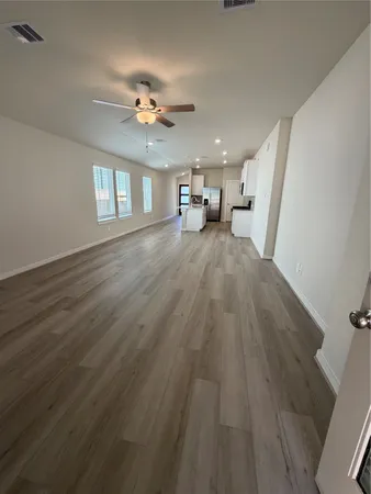 a view of an empty room and chandelier fan