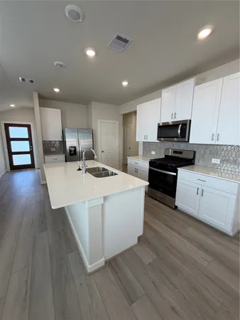 a kitchen with a refrigerator sink and cabinets