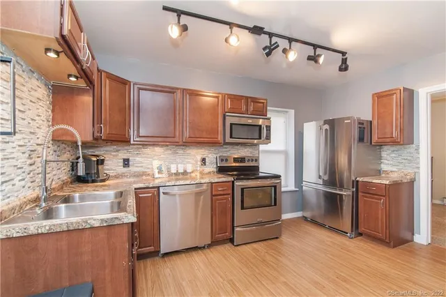 a kitchen with granite countertop a refrigerator stove top oven and sink