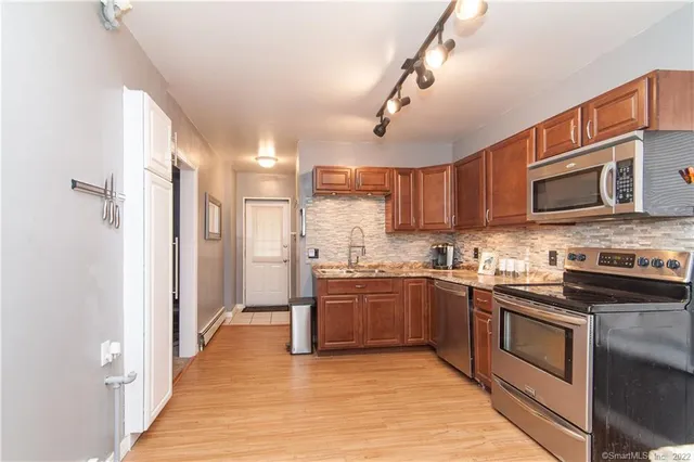 a kitchen with stainless steel appliances granite countertop a stove top oven a sink dishwasher a refrigerator and a microwave oven on the kitchen countertops