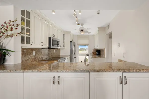 a kitchen with kitchen island granite countertop a sink a counter top space and cabinets