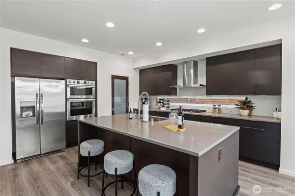 a kitchen with stainless steel appliances a sink stove refrigerator and wooden floor