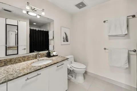 a bathroom with a granite countertop sink a toilet and a mirror