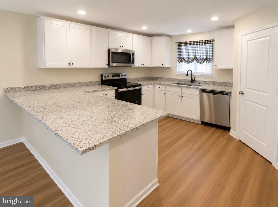 17854 Meriwether Lewis Street Ruther Glen, VA 22546 - Photo 7 of 35 a kitchen with stainless steel appliances granite countertop a sink dishwasher a stove top oven a refrigerator with white cabinets and wooden floor