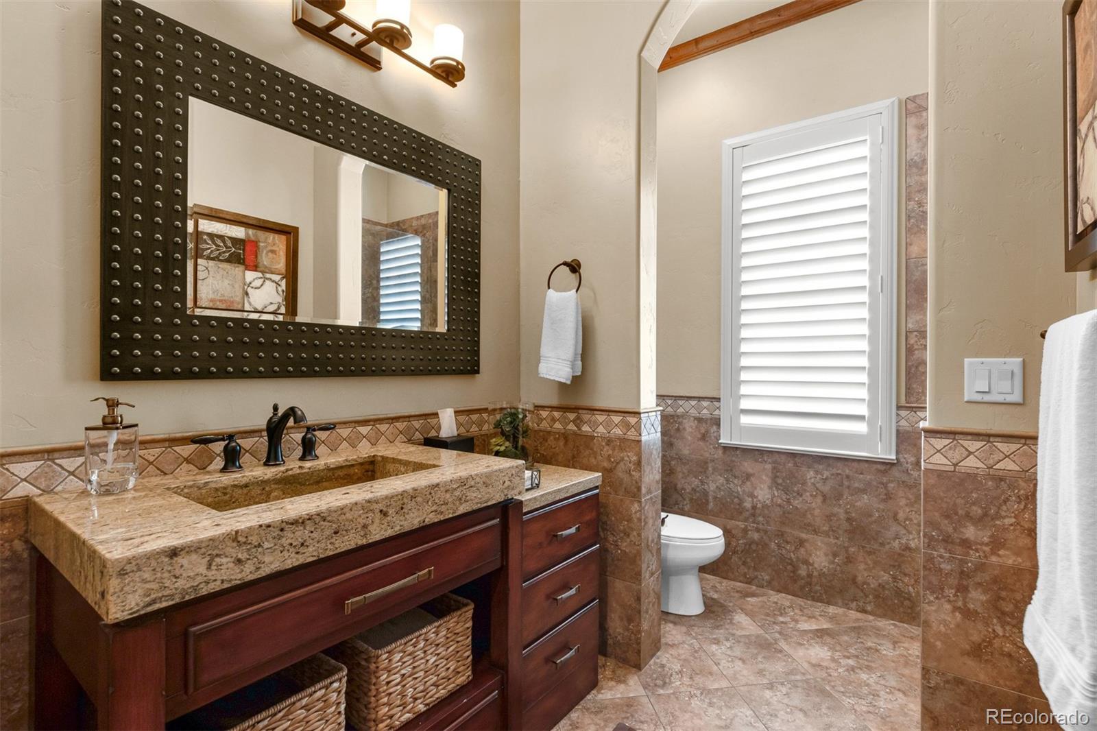 981 Buffalo Ridge Road Castle Pines, CO 80108 - Photo 12 of 39 a bathroom with a granite countertop sink a toilet and mirror