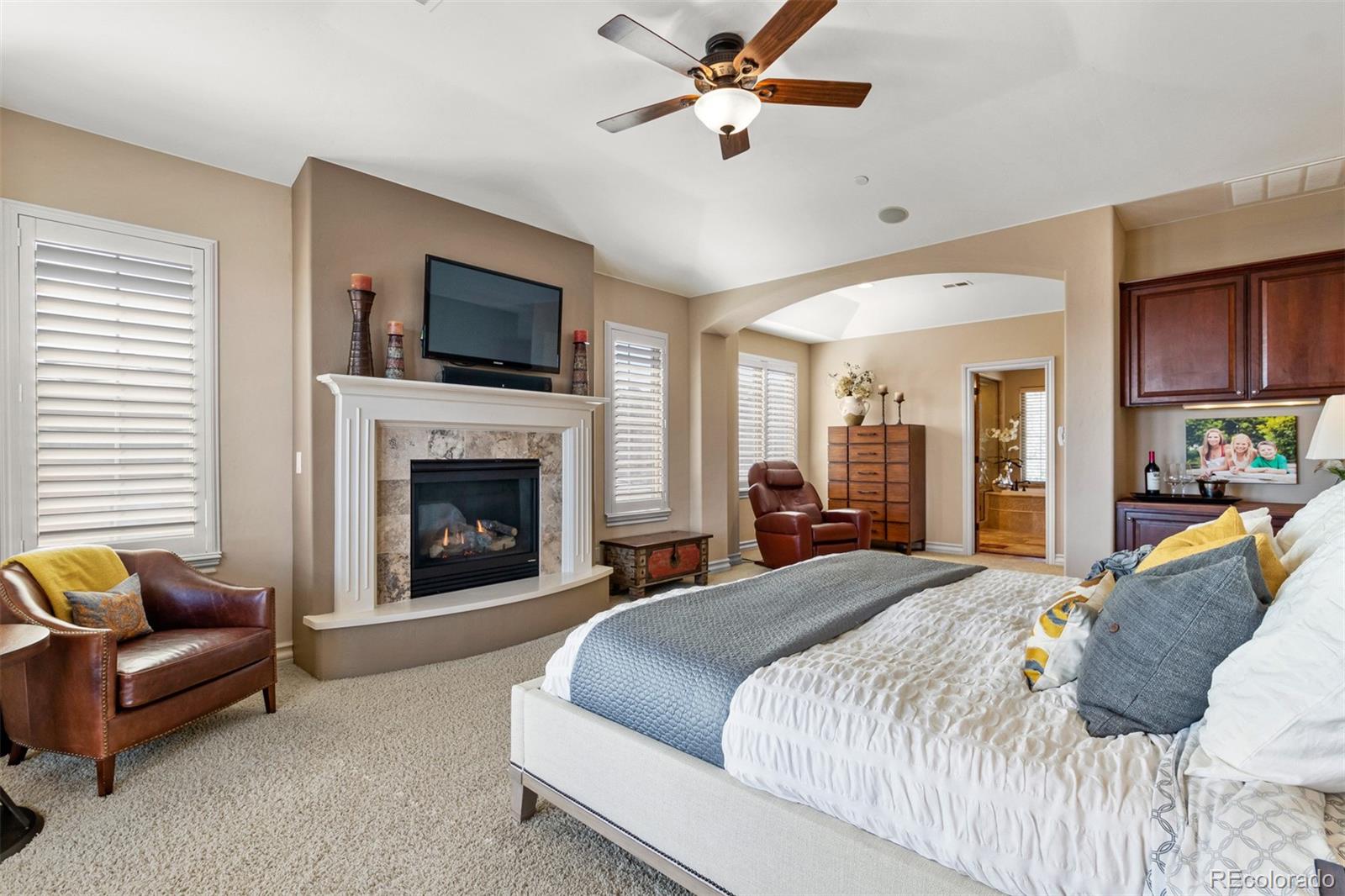 981 Buffalo Ridge Road Castle Pines, CO 80108 - Photo 18 of 39 a spacious bedroom with a large bed and a fireplace