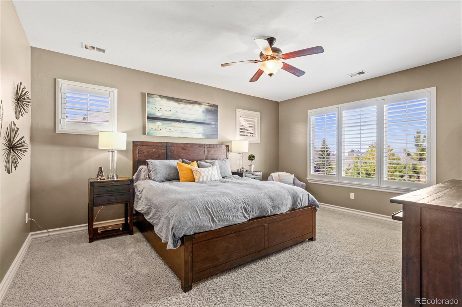 981 Buffalo Ridge Road Castle Pines, CO 80108 - Photo 22 of 39 a spacious bedroom with a large bed and a chandelier