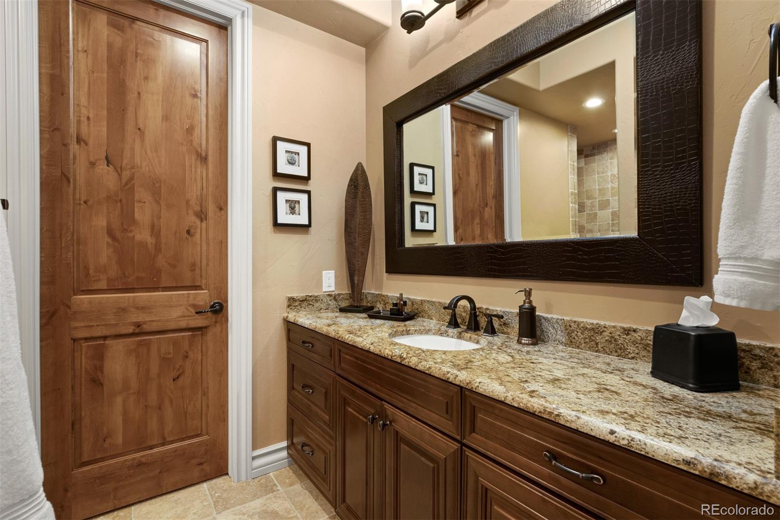 981 Buffalo Ridge Road Castle Pines, CO 80108 - Photo 31 of 39 a bathroom with a granite countertop sink and a mirror