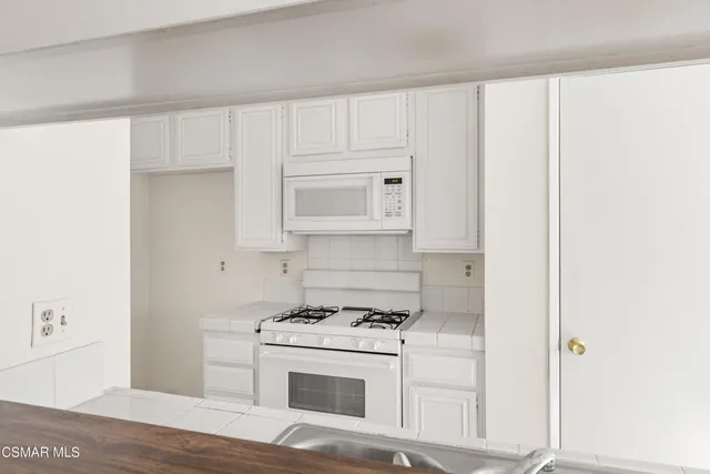 a kitchen with white cabinets and white appliances