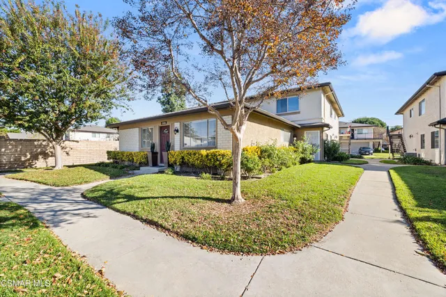 a view of a white house with a yard and potted plants