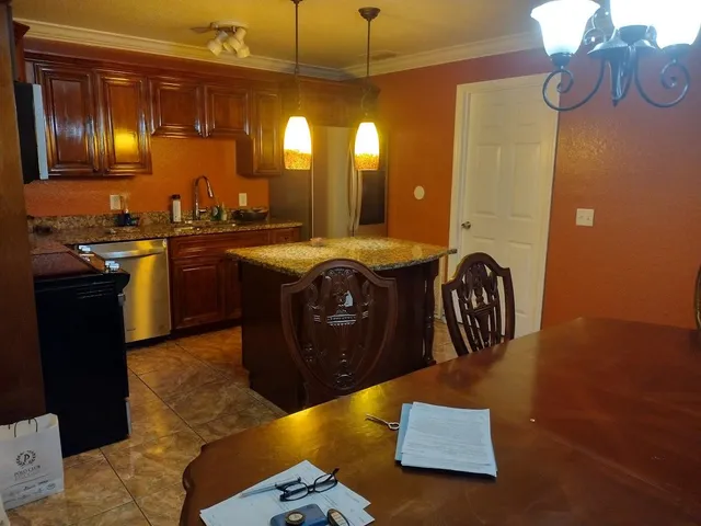 a kitchen with granite countertop a sink a stove top oven and cabinetry